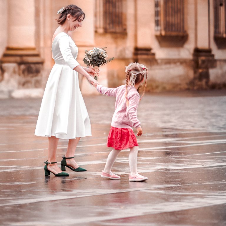 Séance photo d'un photographe de mariage d'une enfant tient la mariée par la main lors d'un mariage à Bordeaux.